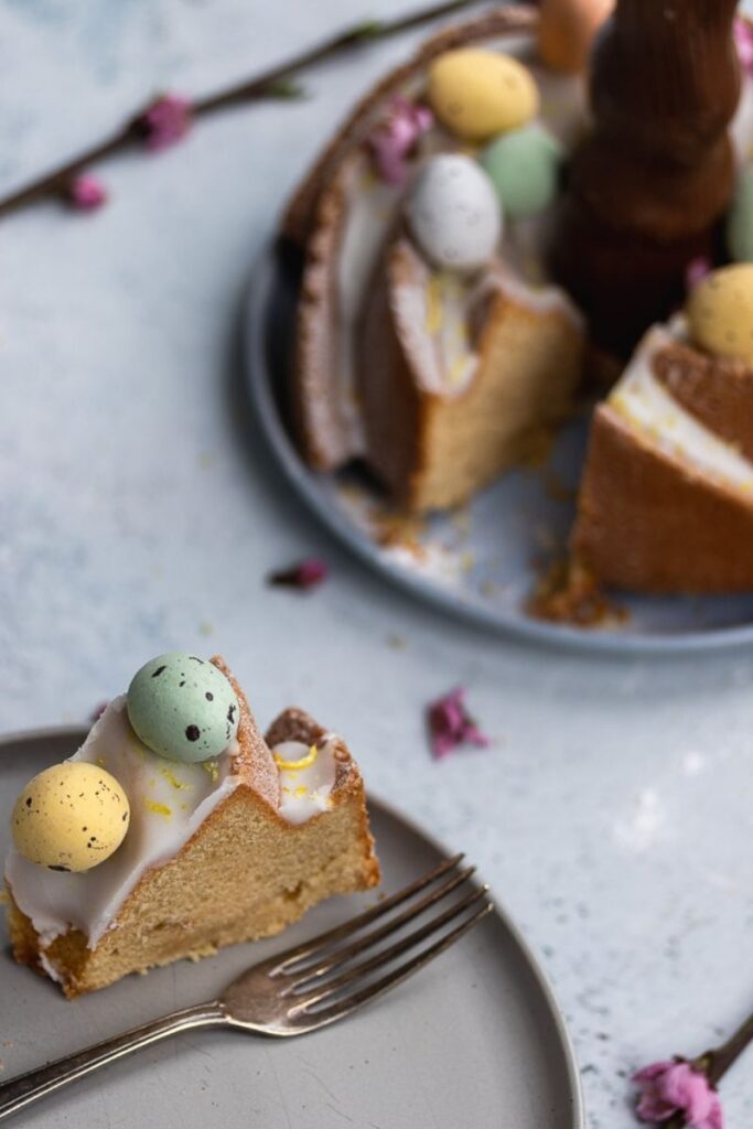 Slice of a lemon bundt cake with Easter eggs and lemon glaze on top.