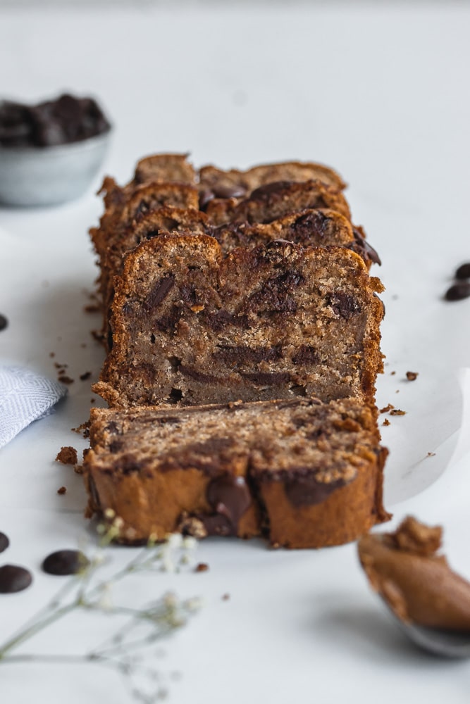 Loaf of peanut butter banana bread with chocolate chips, white background