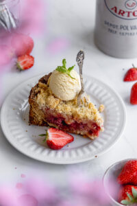 Strawberry crumble pie on a white plate and white background with a scoop of vanilla ice
