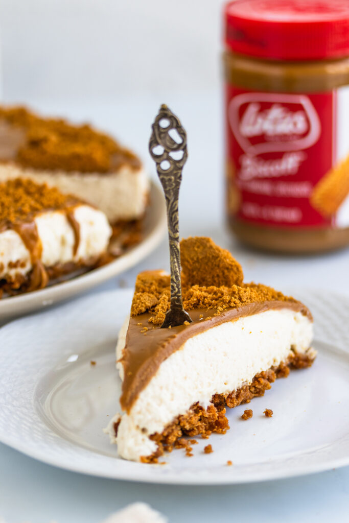 Slice of creamy Biscoff cheesecake topped with Biscoff Spread and crushed Biscoff cookies.